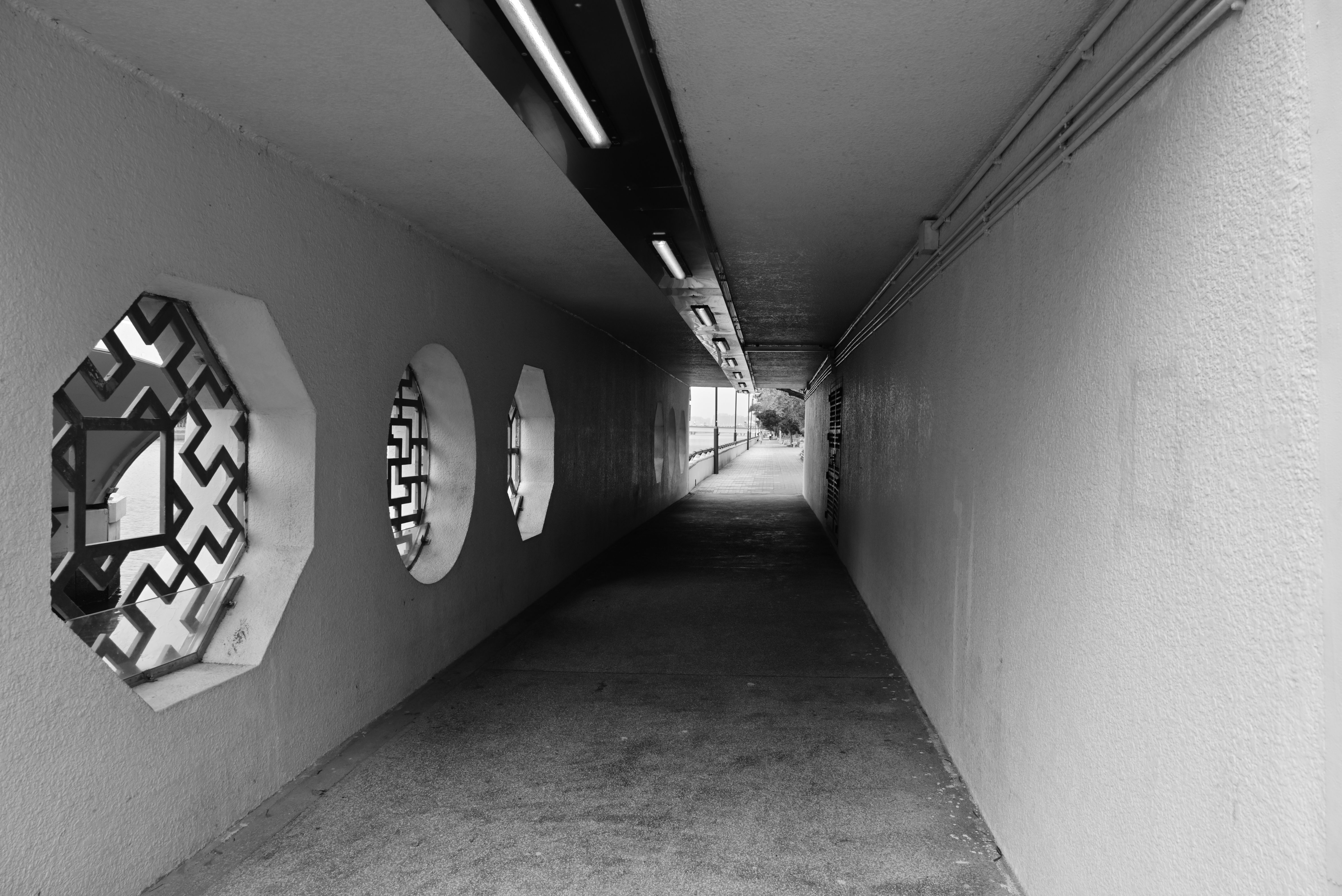 Black and white photo of a modern urban tunnel featuring unique geometric windows.