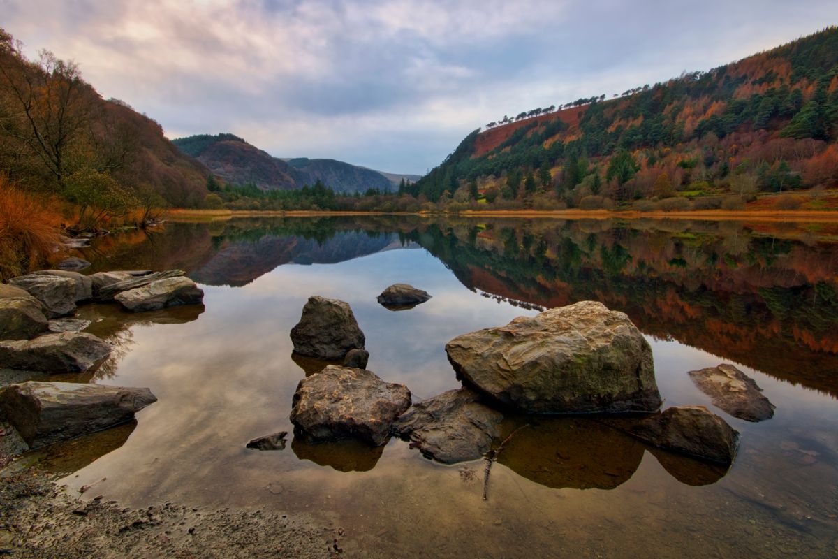 Autumn foliage reflected in calm waters at Glendalough Lake, Ireland