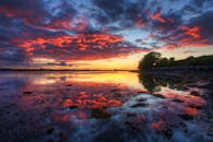 湖面平静，日落令人惊叹，云层与倒影格外引人注目