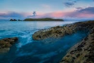 黄昏时分，北爱尔兰海岸一片宁静，海景中可见多岩石的海岸和远处的岛屿