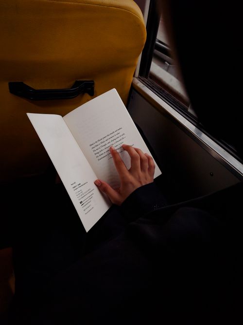 Free Close-up of a person reading a book during a bus ride in Coimbatore, India. Stock Photo