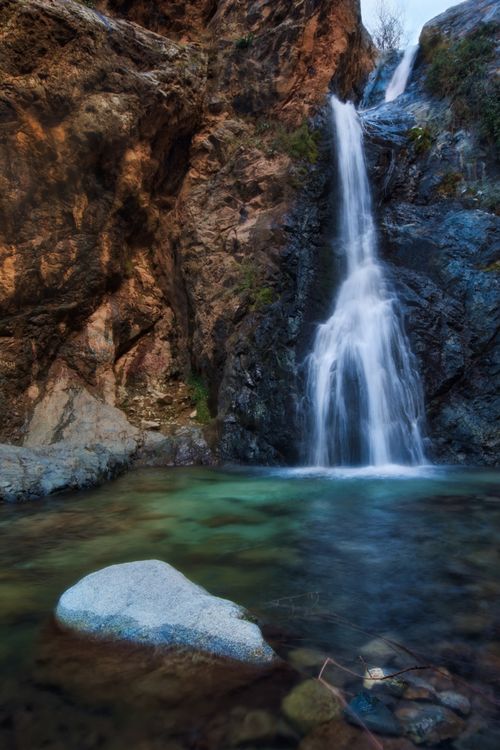 Free Beautiful waterfall flowing through rocky terrain with crystal clear water below. Stock Photo
