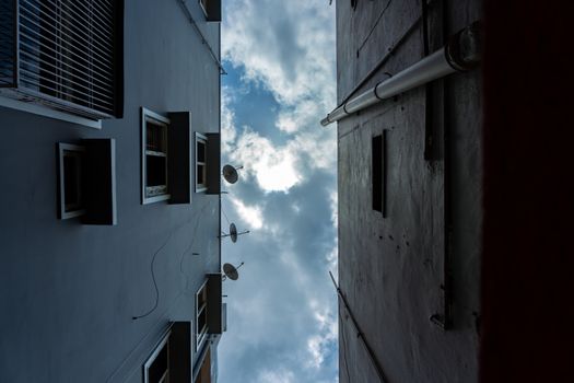 Upward city view captures symmetrical building facades and a cloudy sky.