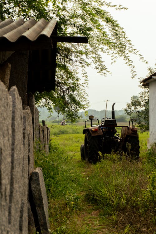 An Old Tractor between Buildings in the Countryside 