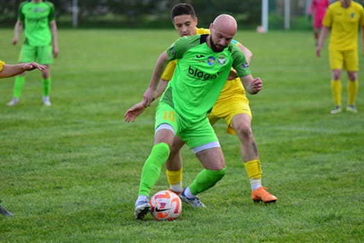 Players in vibrant jerseys compete fiercely in a soccer match on lush green field.