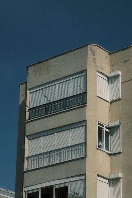 Free Low angle view of a sunlit urban building with closed shutters against a clear sky. Stock Photo