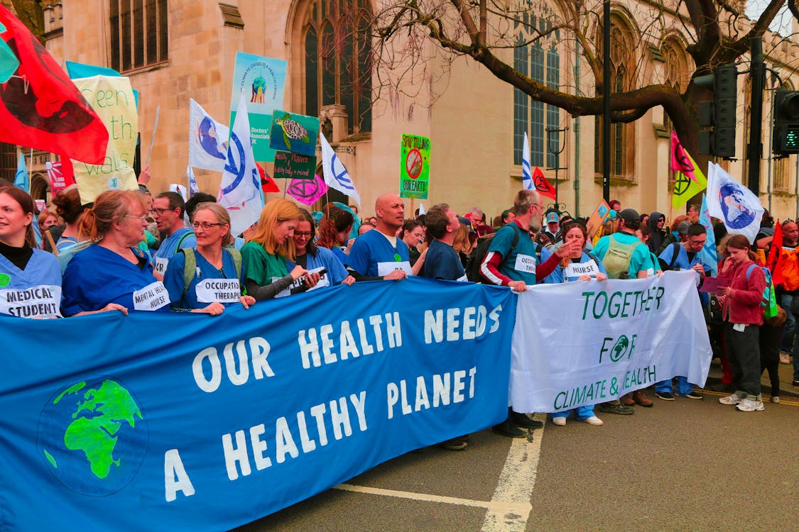 People Holding Banners during a Climate Protest on a Street in City 