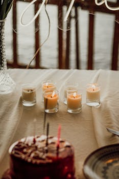 A warm and inviting table setting with lit candles and a delicious cake, perfect for celebrations.