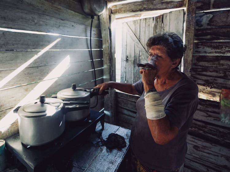 Elderly Woman Cooking And Smoking A Cigar 