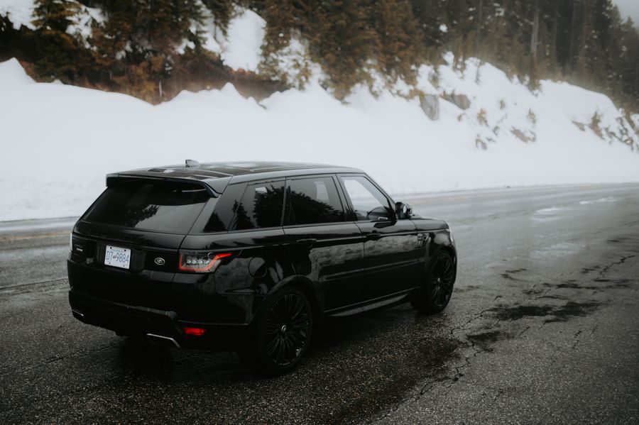 SUV negru pe un drum de iarnă între munți înzăpeziți