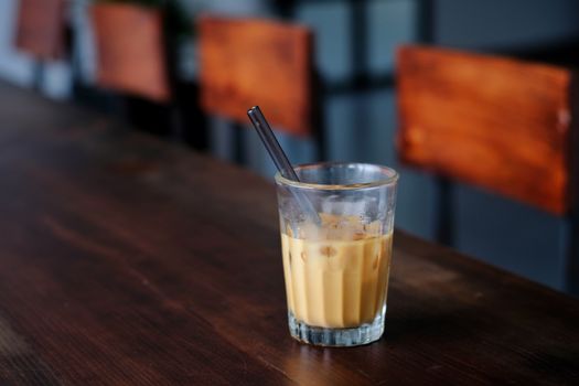 A refreshing iced coffee served in a glass with a metal straw on a rustic wooden table.