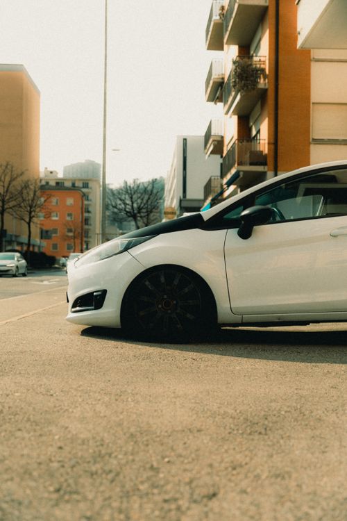 Free A white Ford Fiesta parked on a sunlit street in Lugano, Switzerland. Stock Photo