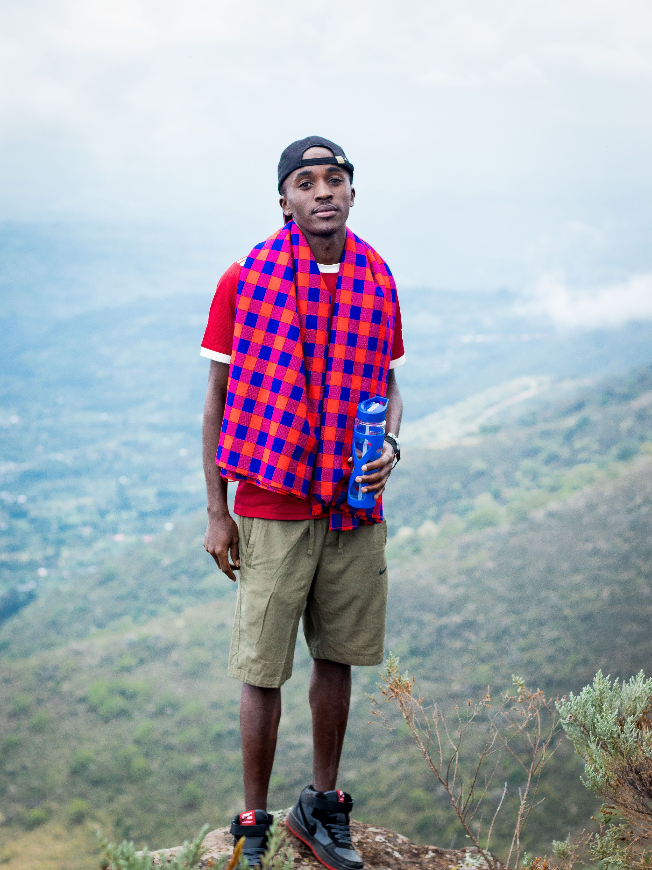 An adult male hiker standing on a cliff with scenic views in Nyeri County, Kenya.