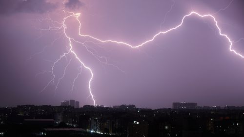 Free Stunning lightning bolts illuminate a cityscape during a nighttime thunderstorm. Stock Photo