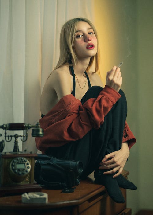 Smoking Blonde Woman Sitting on a Dresser