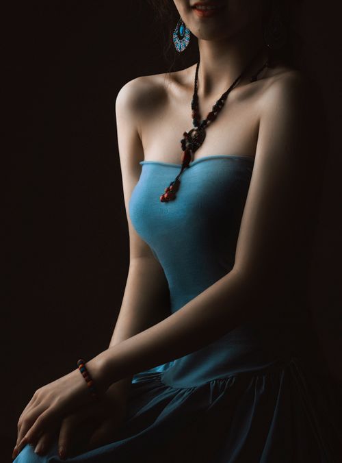Free Stylish portrait of a woman in a blue dress with striking jewelry on a black background. Stock Photo
