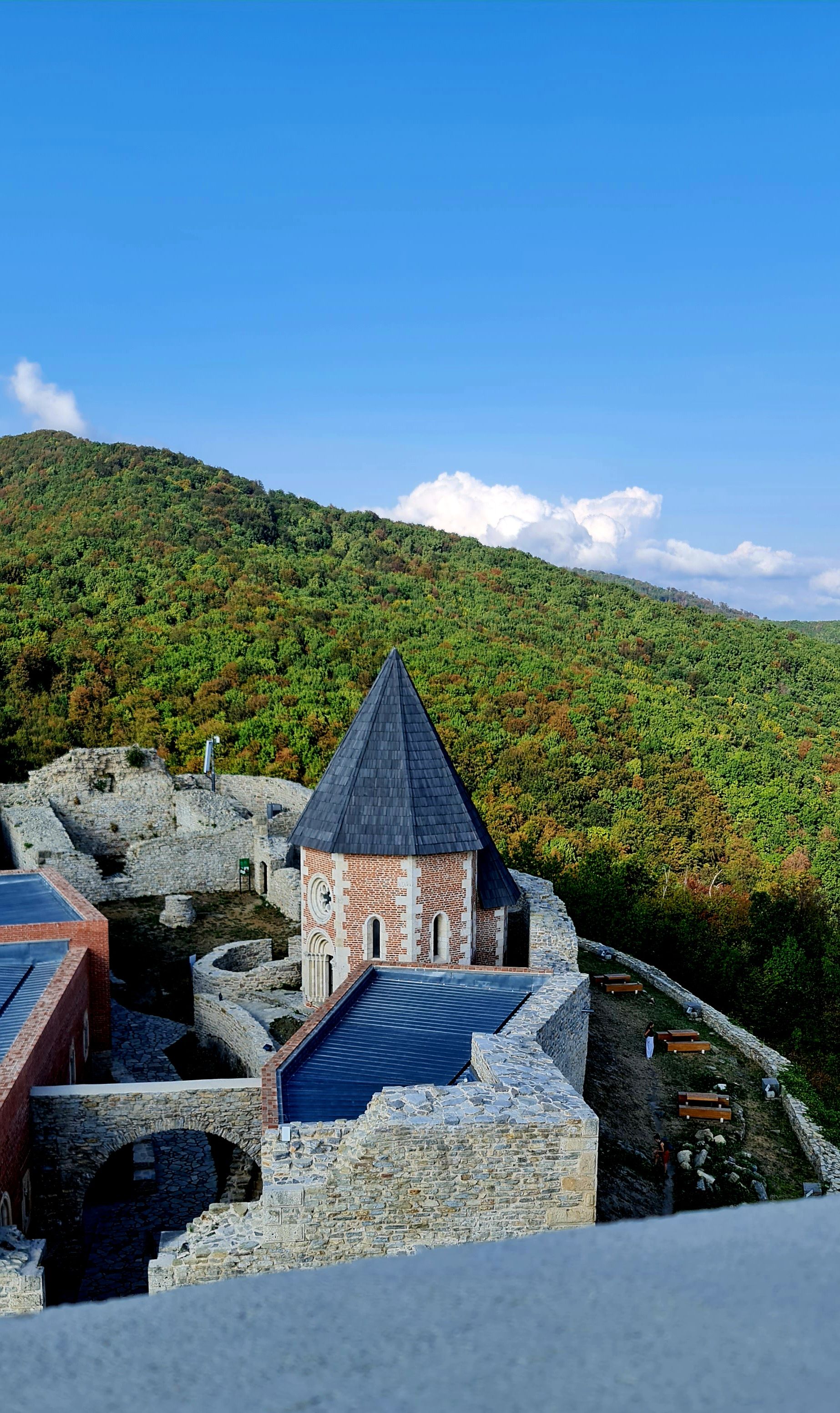 A captivating view of Medvedgrad Castle surrounded by lush hills under a bright, clear sky.