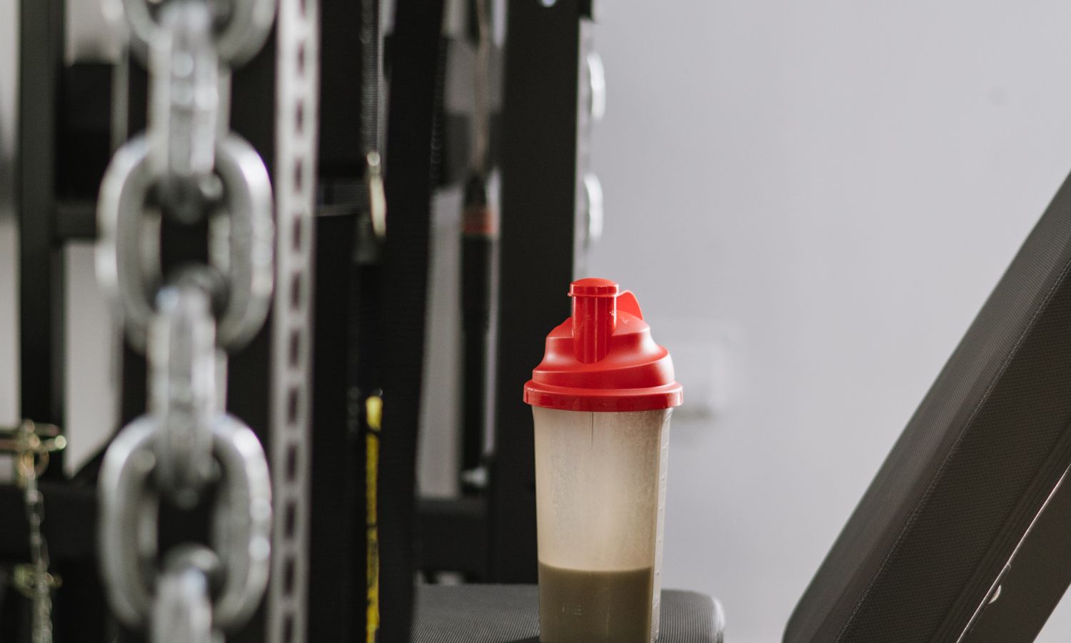 Batido de proteína sobre una máquina de gimnasio, suplementación deportiva