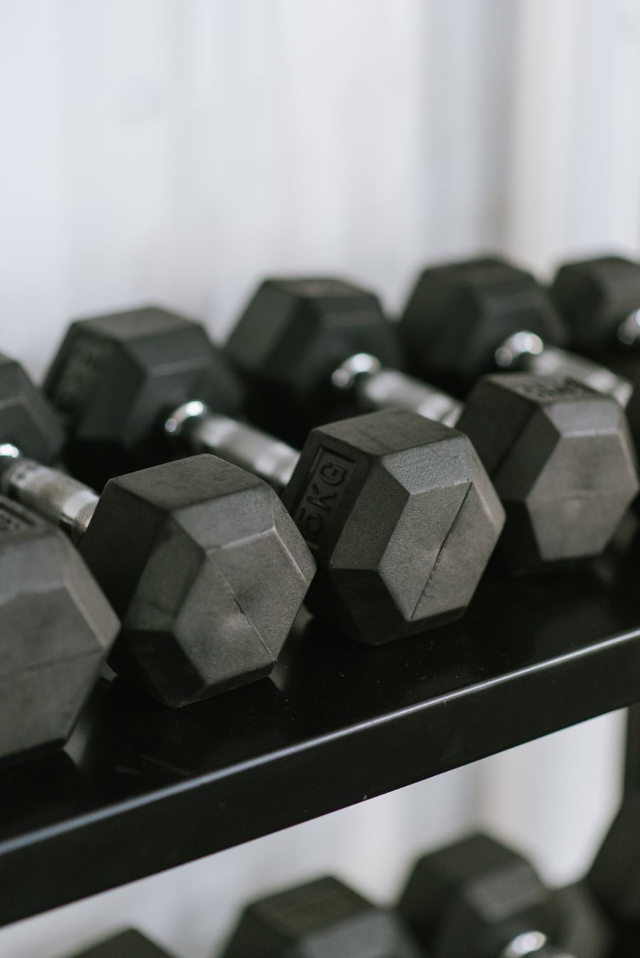 Black hex dumbbells lined up on a gym rack