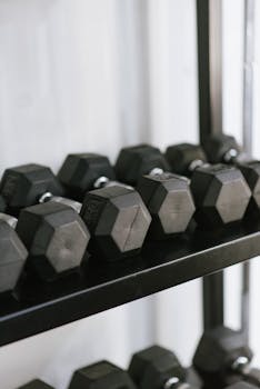 Row of black hexagonal dumbbells neatly stored on gym shelves, ideal for strength training.