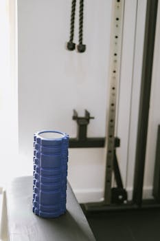 A blue muscle roller sits on a bench in a contemporary gym, highlighting fitness equipment.