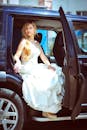 在一个阳光明媚的日子里，优雅的新娘穿着婚纱，优雅地坐在汽车里，准备前往仪式现场