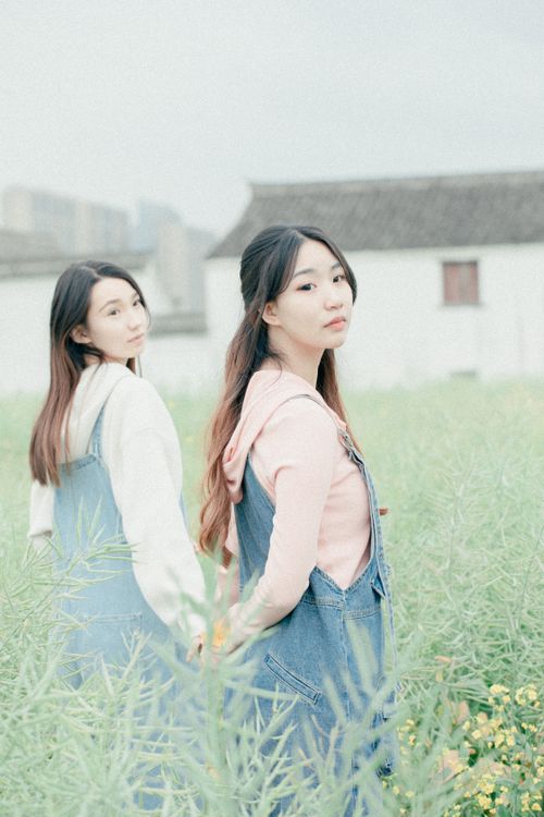 Free Two young women holding hands in a tranquil field, symbolizing friendship and beauty. Stock Photo