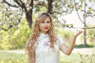 春天，一位穿着传统服装的女人在户外拿着盛开的树枝