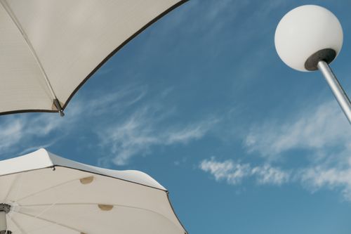 Free White beach umbrellas against a clear blue summer sky. Stock Photo