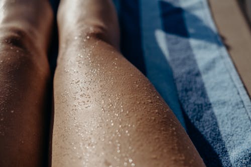 Close-up of Wet Legs of a Person Sitting on a Towel on a Beach 