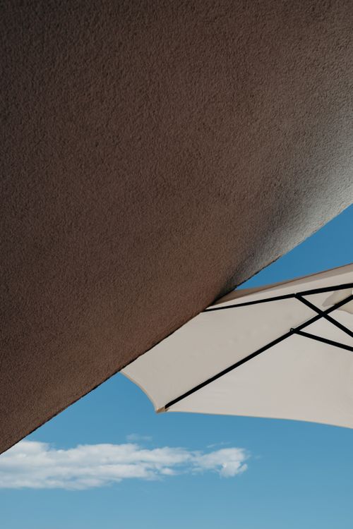 Free Artistic shot of modern building angles and a parasol against a clear blue sky. Stock Photo
