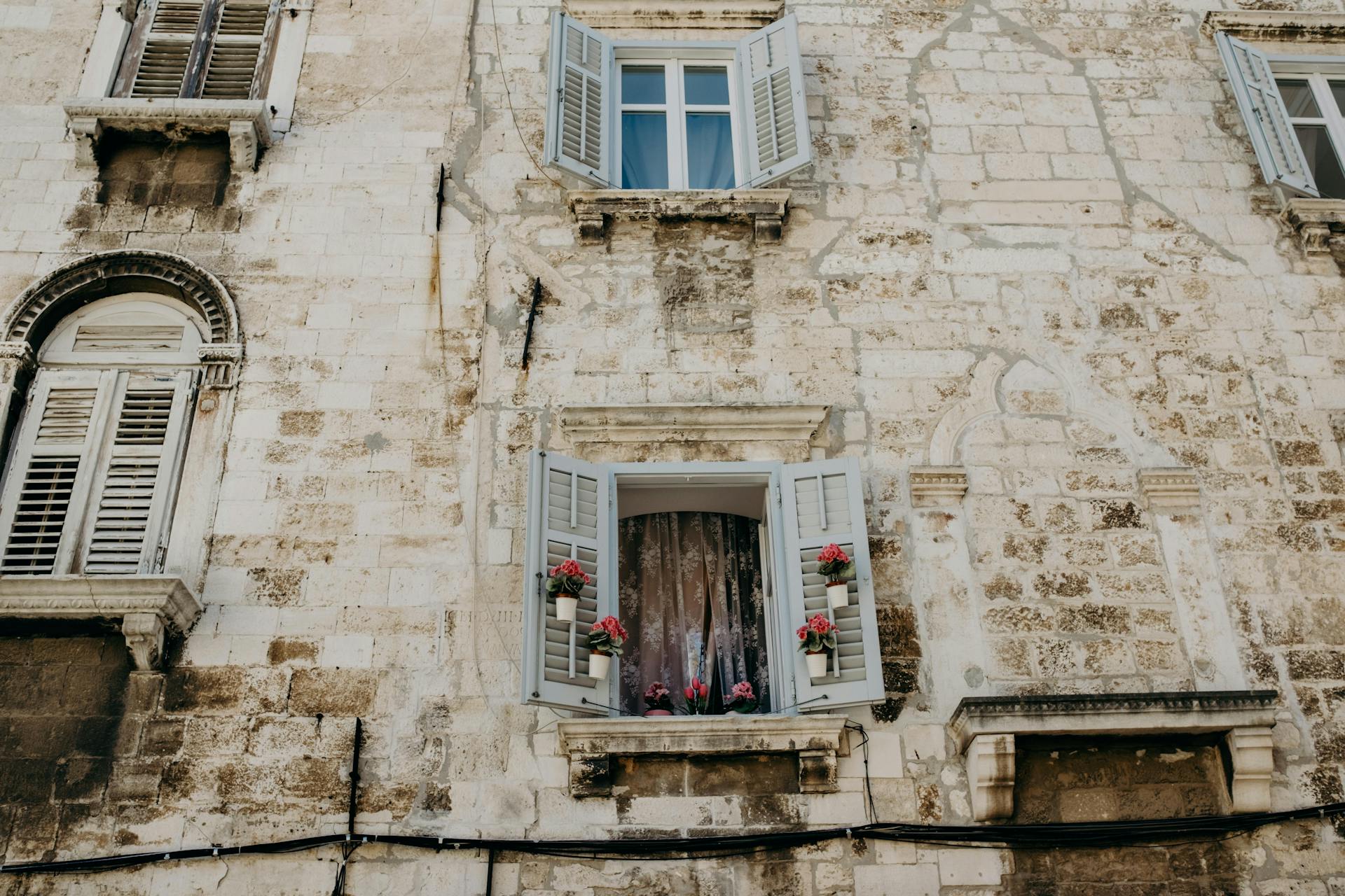 Flowers in Pots on Shutters on House in Croatia