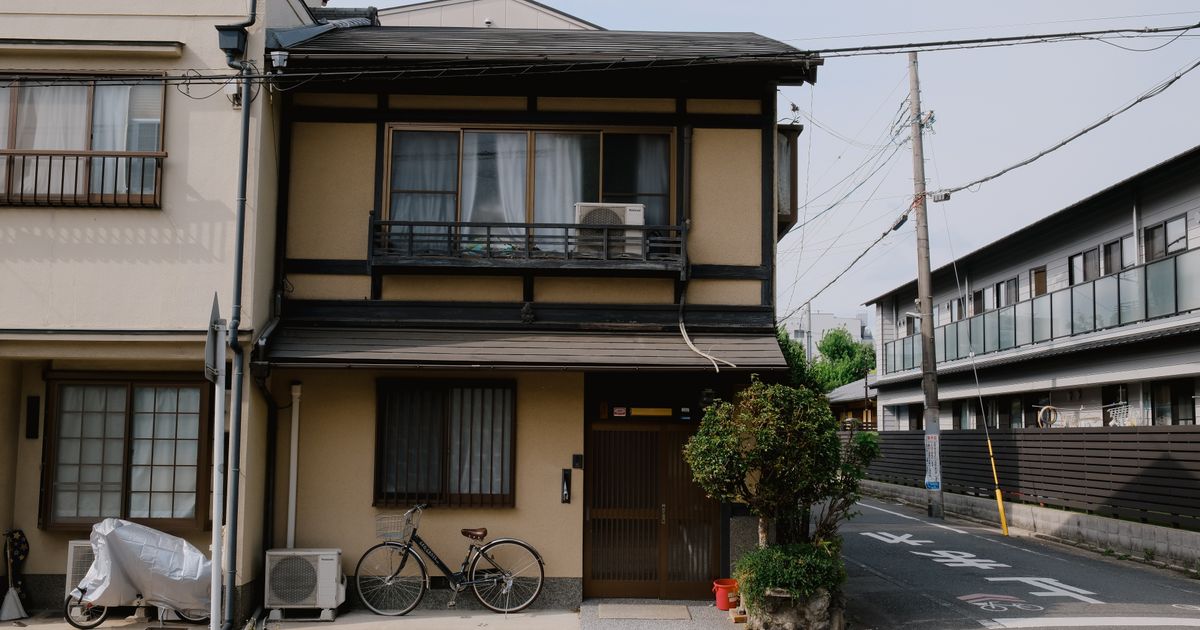 電線の通る道沿いに建つ2階建ての木造住宅