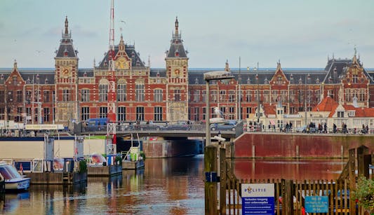 Scenic view of Amsterdam Centraal station and canal, capturing local architecture.