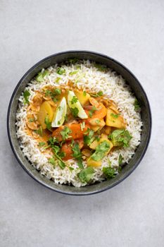 Savory vegan curry with fresh vegetables served on jasmine rice in a bowl.