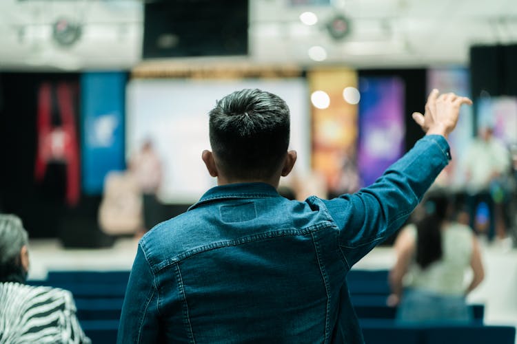 Back View Of A Man In The Audience With His Arm Raised 