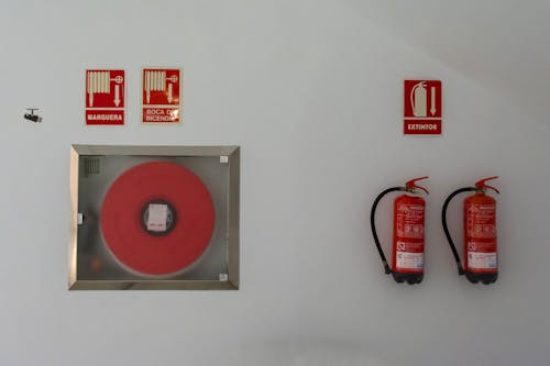 Red Hose and Fire Extinguishers on White Wall