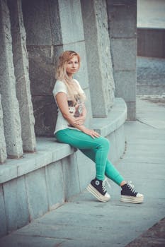 一位穿着休闲服的年轻女子在户外对着石头建筑摆姿势