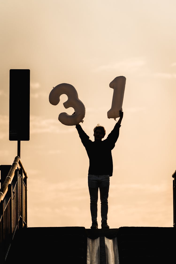 Man Holding Inflatable Numbers 3 And 1 