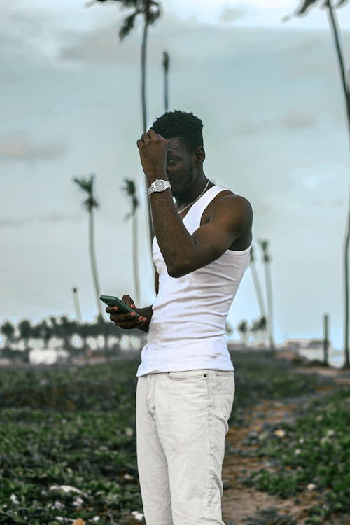 Man in a White Outfit Standing on a Field with Palm Trees 