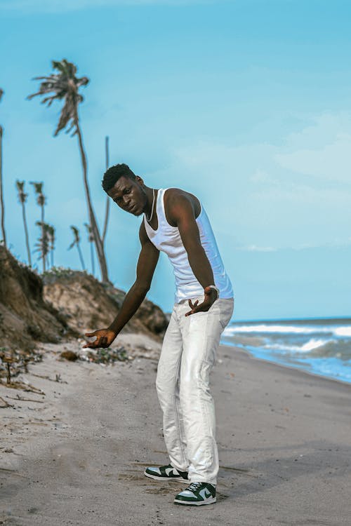 Man in a Tank Top and Pants Standing on the Tropical Beach 