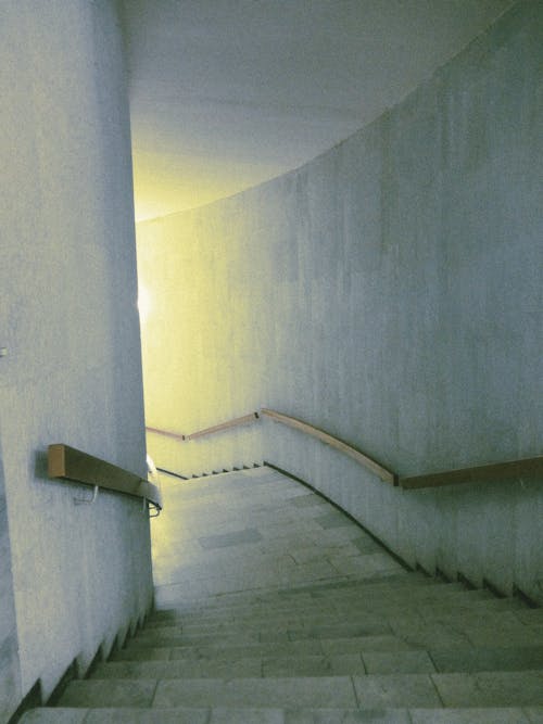 An Empty Staircase between White Walls Leading Down