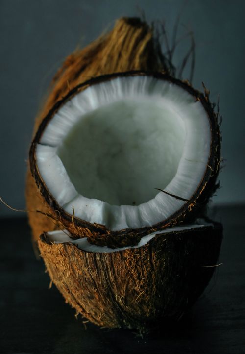 Free A detailed view of a freshly cracked coconut showcasing the white flesh and fibrous shell. Stock Photo