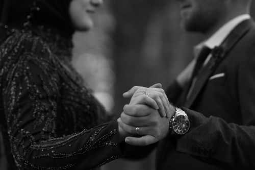 Free A couple elegantly holding hands, showcasing their engagement and jewelry in a black and white setting. Stock Photo