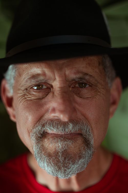 Free Close-up portrait of a senior man with a beard and hat, expressing a thoughtful gaze. Stock Photo