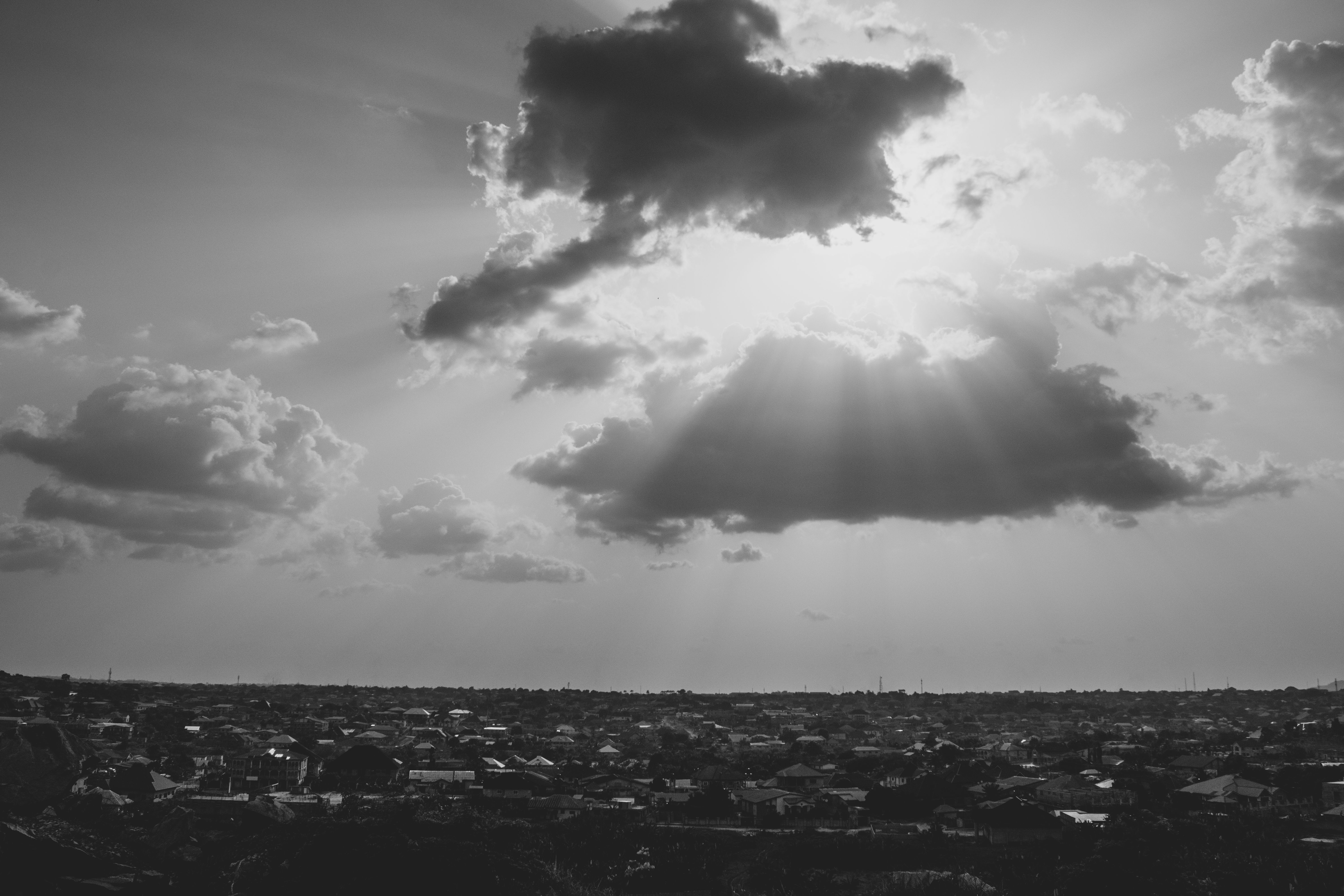 Striking cityscape with sunbeams breaking through clouds over an urban skyline.