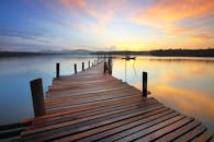 在日出时分，一个宁静的木制码头延伸到平静的湖面，倒映着五颜六色的天空