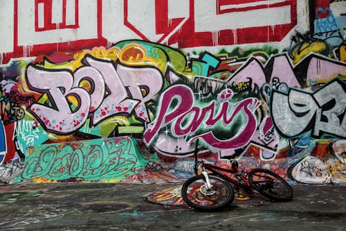 A Bicycle Lying on the Ground in front of a Wall with Graffiti 