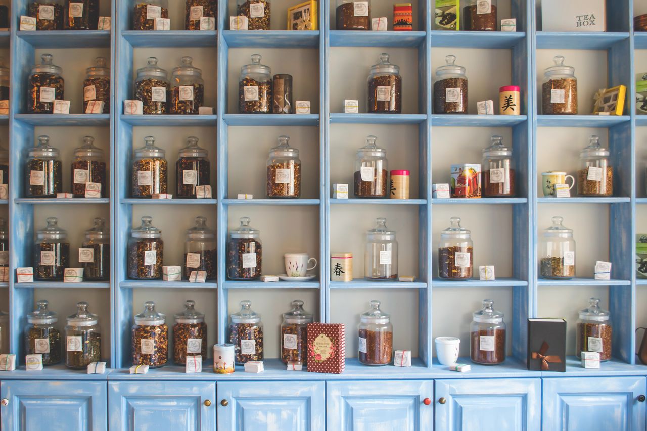 Organized display of herbal tea jars on vibrant blue shelves in a shop.