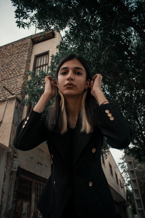 Free Fashionable woman in formalwear adjusting hair in an urban environment. Stock Photo